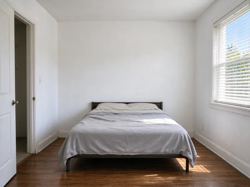 Bare upper wall above a bed in a small San Diego bedroom before a mini split head is installed