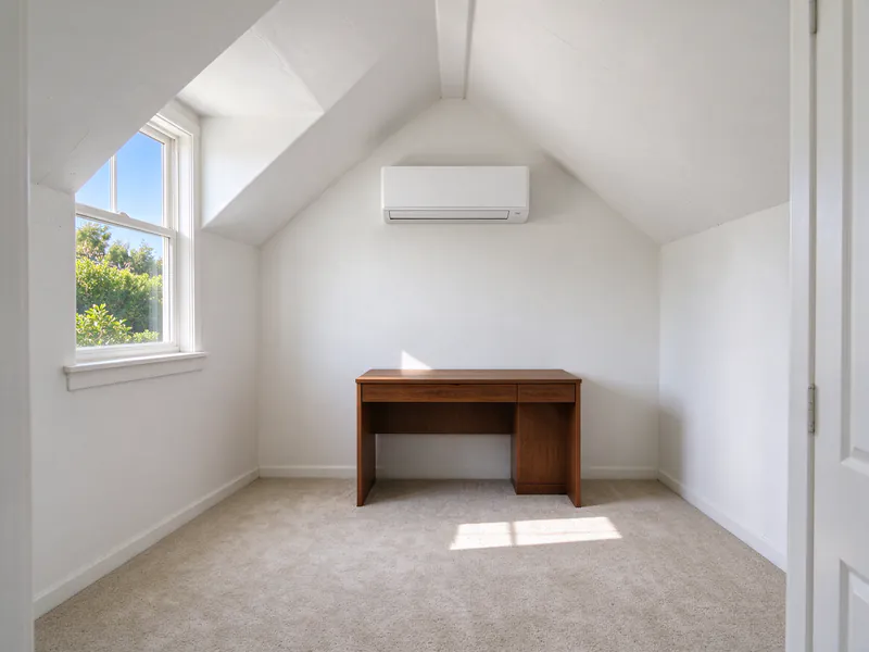 Bonus room over a garage with a sloped ceiling and a white mini split head on the gable end wall