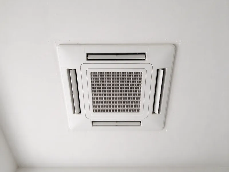 Four-way grille of a ceiling cassette mini split flush with a white ceiling