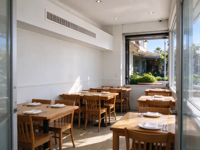 Linear supply grille in a drywall soffit above the dining tables of a small restaurant