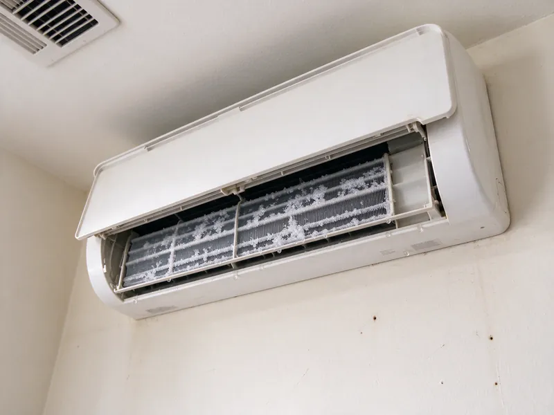 White frost coating the coil inside a mini split indoor head with its front panel lifted